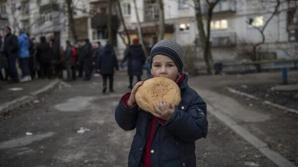 Ребенок с хлебом во время раздачи гуманитарной помощи жителям города отделением Донбасс мотоклуба Ночные волки в Рубежном - Sputnik Азербайджан