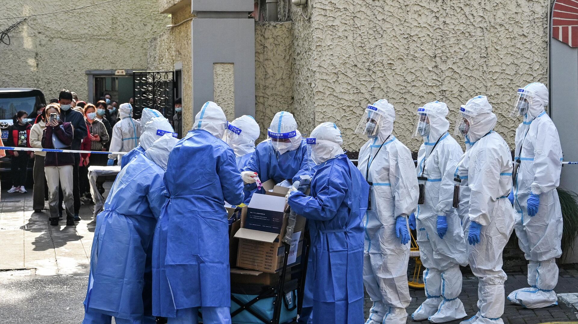 Медицинские работники в защитных костюмах готовят оборудование перед тестированием людей на Covid-19 в жилом комплексе в Шанхае - Sputnik Азербайджан, 1920, 13.04.2022