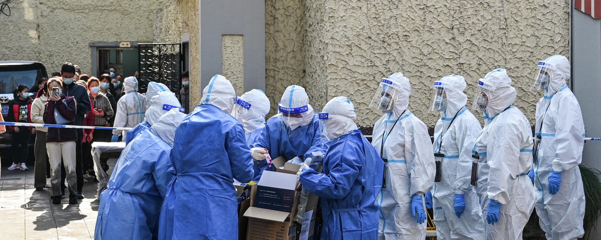 Медицинские работники в защитных костюмах готовят оборудование перед тестированием людей на Covid-19 в жилом комплексе в Шанхае - Sputnik Азербайджан, 1920, 11.02.2024