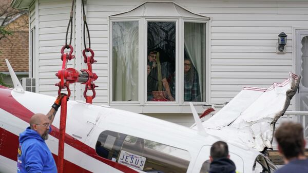 Сотрудники службы экстренной помощи работают над удалением самолета, разбившегося в жилом районе в Манвилле, США - Sputnik Азербайджан