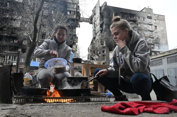 Жители Мариуполя готовят еду во дворе разрушенного дома  - Sputnik Азербайджан
