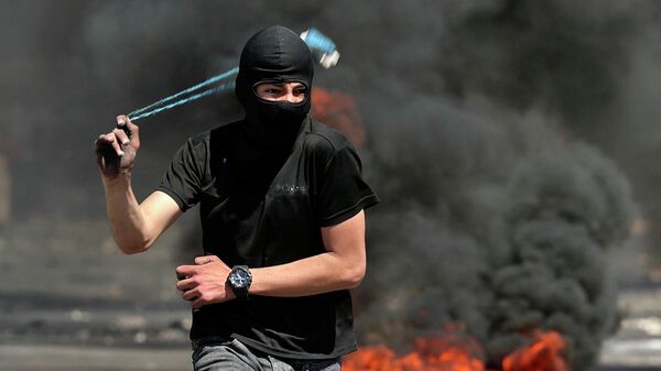 Палестинский протестующий бросает камень в сотрудников израильской службы безопасности - Sputnik Азербайджан