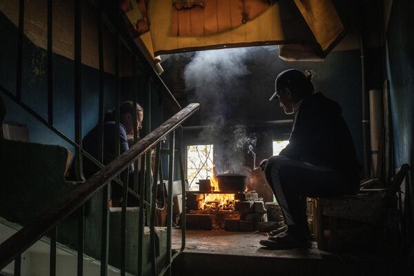Местные жители готовят еду на лестничном пролете в подъезде своего дома в Мариуполе - Sputnik Азербайджан