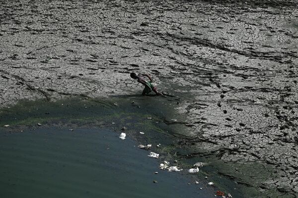 Мальчик идет по пересохшему руслу реки Ямуна в жаркий день в Нью-Дели, Индия. - Sputnik Азербайджан