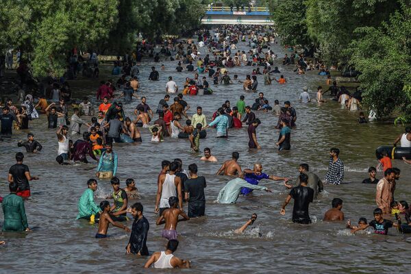 Люди охлаждаются в канале в жаркий летний день в Лахоре, Индия. - Sputnik Азербайджан