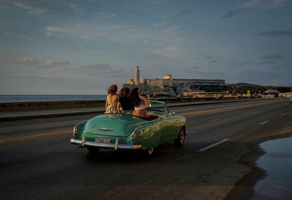 Девушки путешествуют по Малекону на старинном американском автомобиле в Гаване, Куба. - Sputnik Азербайджан