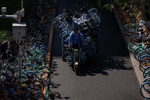 Работник развозит общественные велосипеды, неиспользуемые из-за коронавируса и режима изоляции в Пекине, Китай. - Sputnik Азербайджан