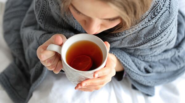 Больная девушка с чашкой горячего чая в постели - Sputnik Азербайджан