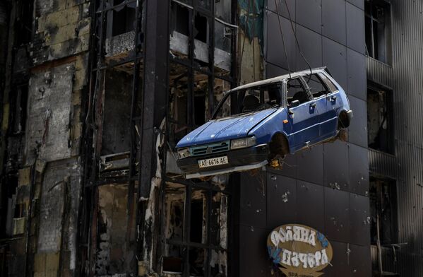 Служба МЧС РФ загружает при помощи крана на трал поврежденный автомобиль в Мариуполе - Sputnik Азербайджан