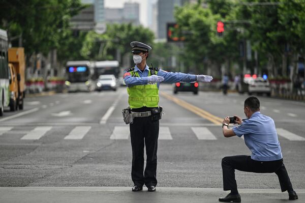Офицер фотографирует регулировщика в районе Цзинъань в Шанхае 1 июня 2022 года, после окончания локдауна. - Sputnik Азербайджан