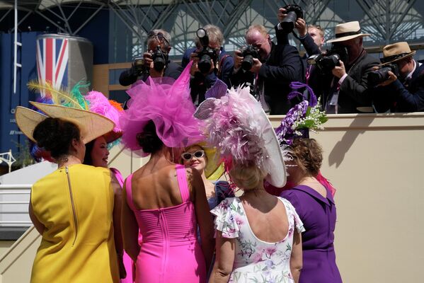 Женщины в шляпах позируют фотграфам на Королевских скачках на ипподроме Аскот в Аскоте, Англия. - Sputnik Азербайджан
