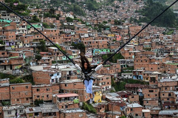 Турист катается на аттракционе в районе Ла-Комуна 13 в Медельине, Колумбия - Sputnik Азербайджан