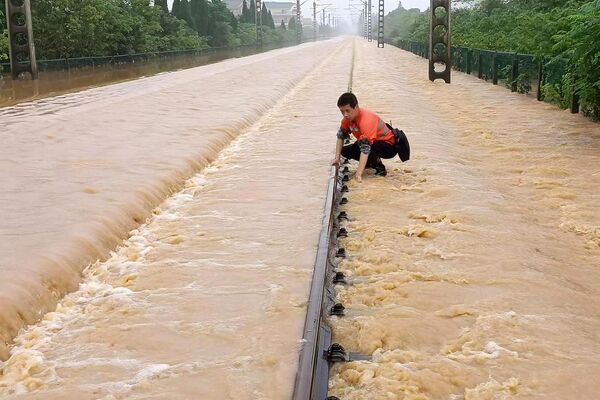 Сотрудник железной дороги проверяет затопленный железнодорожный путь после проливных дождей в Китае. - Sputnik Азербайджан