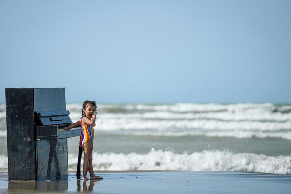 Девочка позирует возле пианино на пляже в Баку. - Sputnik Азербайджан