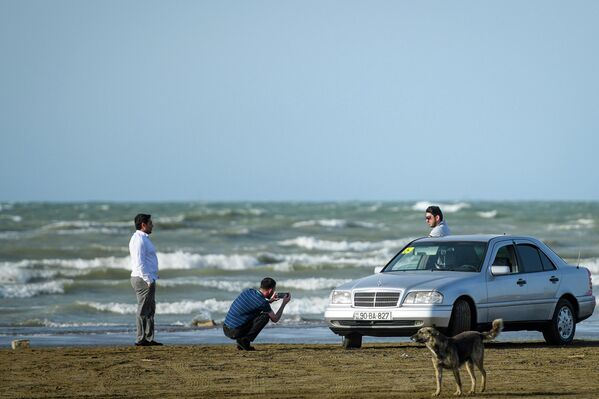 Молодые люди фотографируют машину на берегу моря в Баку. - Sputnik Азербайджан