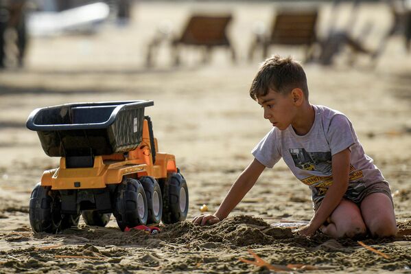 Мальчик играет в песке на пляже в Баку. - Sputnik Азербайджан