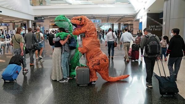 Люди, одетые как динозавры, приветствуют своего друга Джонатана Ромеро в аэропорту Солт-Лейк-Сити. - Sputnik Азербайджан