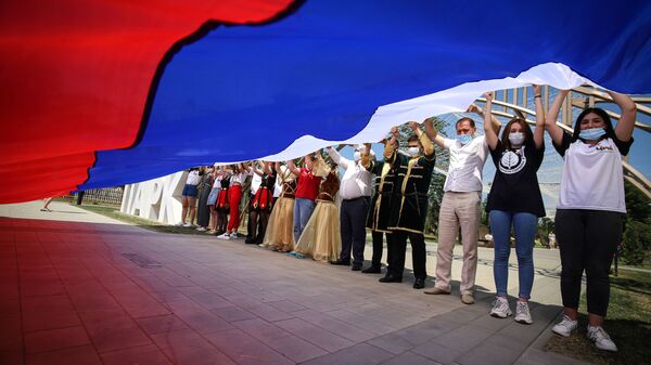 Участники празднований Дня России держат российский флаг в парке Дружбы города Георгиевска Ставропольского края - Sputnik Азербайджан