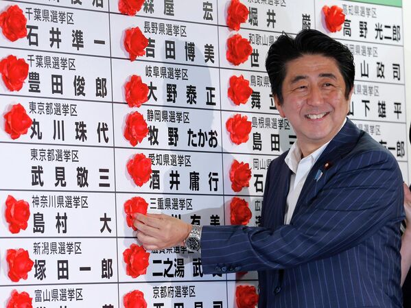 Премьер-министр Японии Синдзо Абэ ставит розетку на имя победившего кандидата от своей Либерально-демократической партии во время подсчета голосов на выборах в верхнюю палату парламента в штаб-квартире партии в Токио. - Sputnik Азербайджан