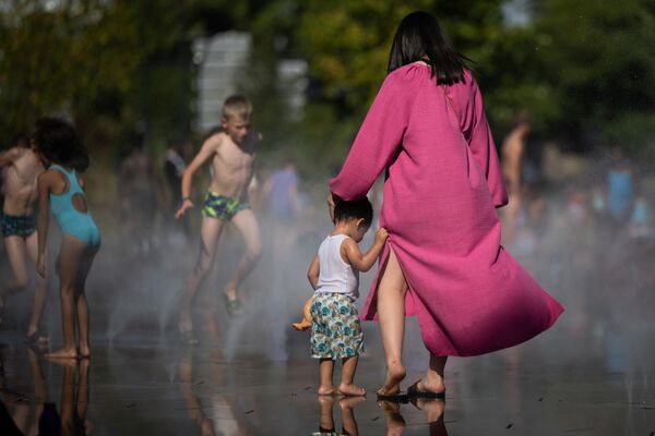 Люди охлаждаются водой из фонтана, поскольку температура воздуха превышает 42 градуса по Цельсию в Нанте. - Sputnik Азербайджан