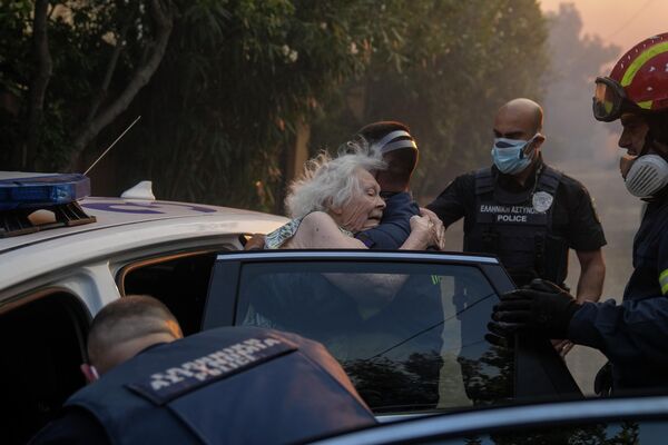 Пожарные и полицейские эвакуируют пожилую женщину из ее дома в Пентели из-за природных пожаров в Греции. - Sputnik Азербайджан