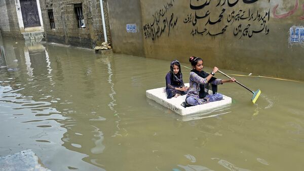 Девочки перебираются на плоту через затопленную после сильных дождей улицу в жилом районе Карачи, Пакистан - Sputnik Азербайджан