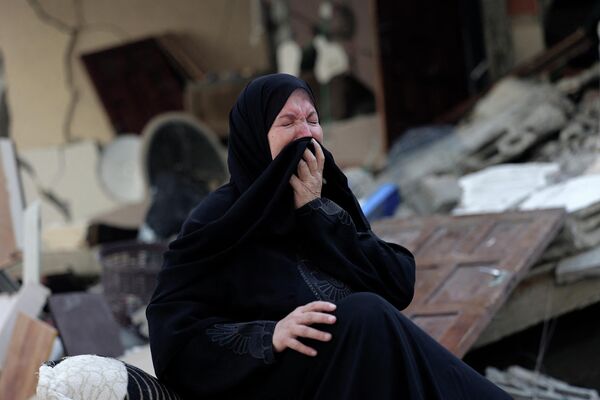 Женщина плачет у разрушенного дома после ударов Израиля по Газе. - Sputnik Азербайджан
