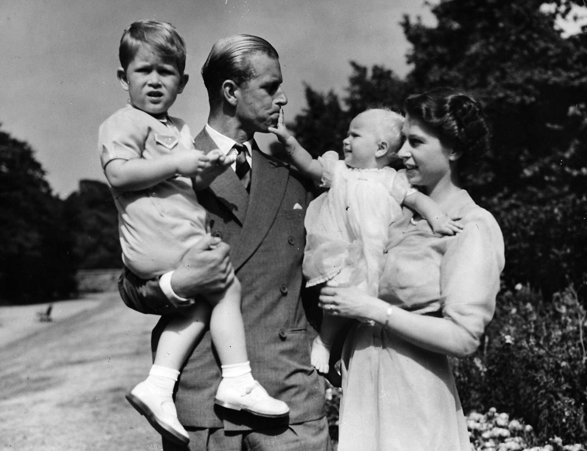 Британская королева Елизавета II, в то время принцесса Елизавета, стоит со своим мужем принцем Филиппом, герцогом Эдинбургским, и их детьми  - Sputnik Азербайджан, 1920, 09.09.2022