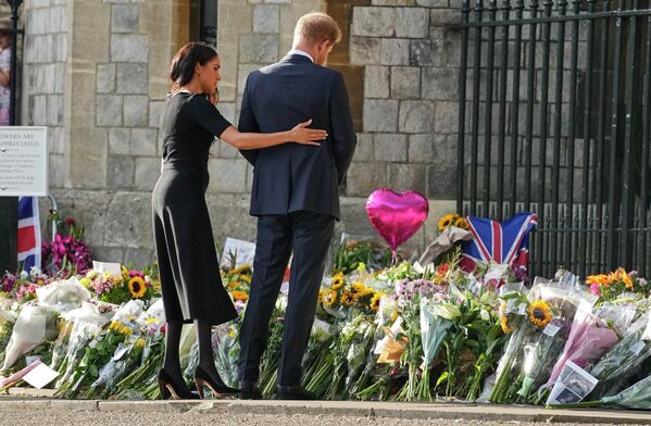 Принц Гарри и Меган, герцогиня Сассекская, смотрят на цветы в честь покойной королевы Елизаветы II возле Виндзорского замка. - Sputnik Азербайджан