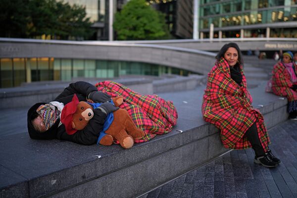 Скорбящая с игрушкой медвежонка Паддингтона спит, стоя в очереди. - Sputnik Азербайджан