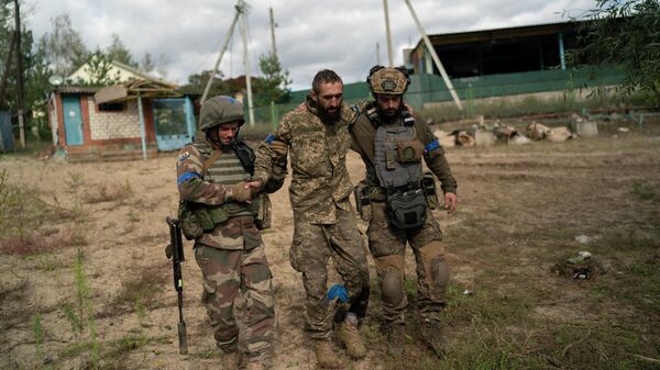 Украинские военнослужащие помогают товарищу во время эвакуации раненых солдат-участников контрнаступления в районе отвоеванного села Щурово, Украина - Sputnik Азербайджан