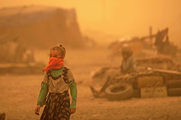 Девушка закрывает лицо во время песчаной бури в лагере для беженцев в пригороде Ракки на севере Сирии. - Sputnik Азербайджан