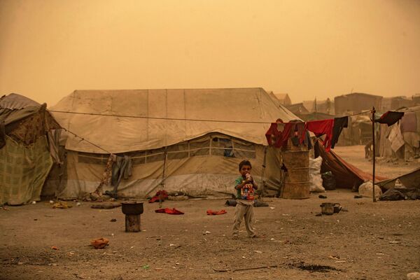 Мальчик пьет из бутылки во время песчаной бури в лагере для беженцев в пригороде Ракки на севере Сирии. - Sputnik Азербайджан