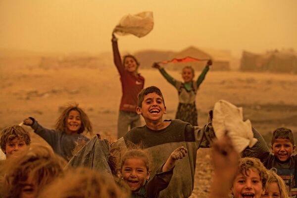 Suriyanın şimalındakı Rəqqa ətrafında yerləşən qaçqın düşərgəsində uşaqlar qum fırtınası zamanı oynayırlar. - Sputnik Azərbaycan
