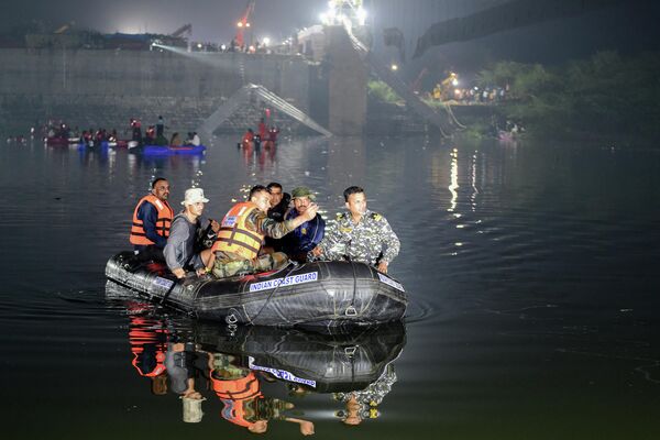 Индийские спасатели проводят поисковые работы после обрушения моста через реку Маччху в городе Морви, Индия. - Sputnik Азербайджан