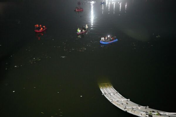 Спасатели ведут поиски пропавших в реке Мачху рядом с обрушившимся мостом в городе Морви, Индия. - Sputnik Азербайджан