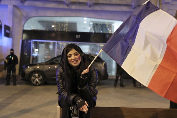 Женщина с флагом на Елисейских полях празднует победу Франции над Марокко в полуфинальном матче ЧМ-2022. - Sputnik Азербайджан