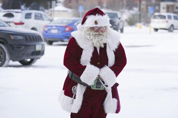 Санта-Клаус идет по заснеженной парковке, в Де-Мойне, штат Айова. - Sputnik Азербайджан