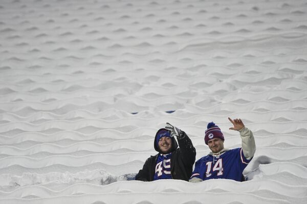 Фанаты Buffalo Bills сидят на заснеженных сиденьях во время разминки перед футбольным матчем между Buffalo Bills и Miami Dolphins в Орчард-парке, штат Нью-Йорк. - Sputnik Азербайджан