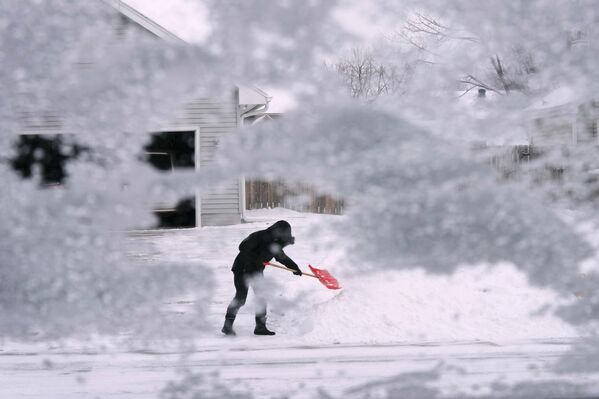 Местный житель сгребает снег с подъездной дорожки в Урбандейле, штат Айова. - Sputnik Азербайджан