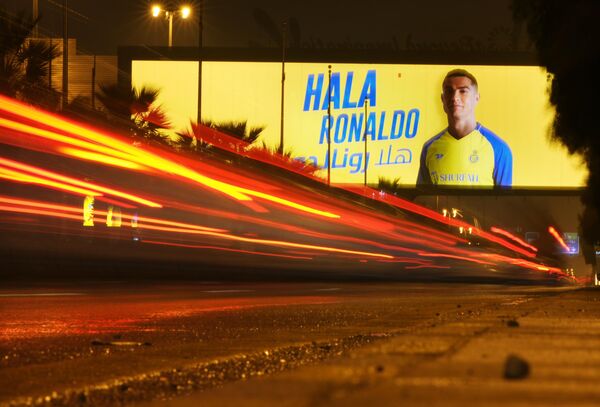 Автомобиль проезжает под рекламным щитом, на котором изображен Криштиану Роналду с арабской надписью «Добро пожаловать, Роналду», в Эр-Рияде, Саудовская Аравия. - Sputnik Азербайджан