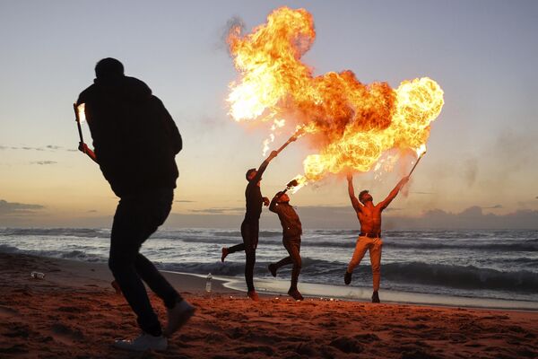 Палестинская молодежь демонстрирует свои навыки огнедышания на пляже в городе Газа, Палестина. - Sputnik Азербайджан
