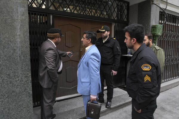 Сотрудники полиции и представители судебных органов разговаривают перед дверью здания посольства Азербайджана в Тегеране, где произошло вооруженное нападение. - Sputnik Азербайджан