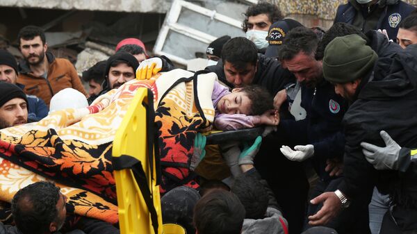 Люди несут девочку, пострадавшую в результате землетрясения в турецком городе Диярбакыр - Sputnik Азербайджан