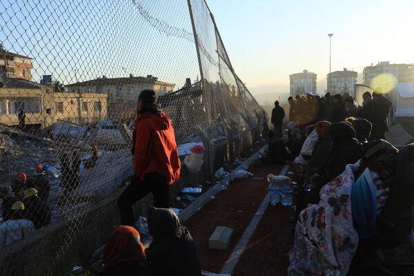 Люди наблюдают, как спасатели и мирные жители ищут выживших под обломками рухнувших зданий в Нурдаги, Турция. - Sputnik Азербайджан