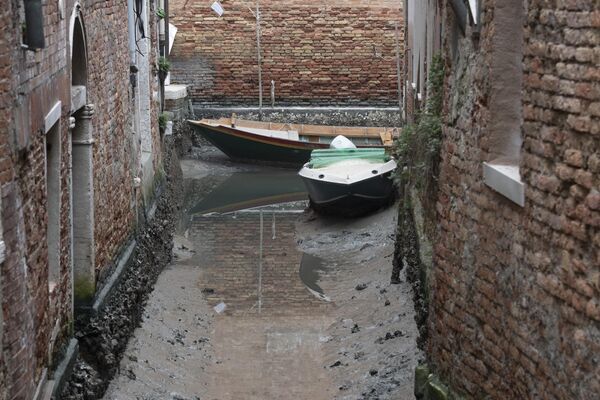Venesiya şəhərində suyun çəkilməsi zamanı kanal boyunca bağlanmış qayıqlar. - Sputnik Azərbaycan