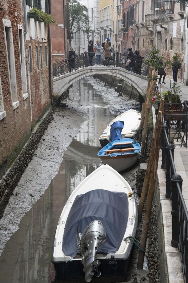 Лодки, пришвартованные вдоль канала во время отлива в Венеции, Италия. - Sputnik Азербайджан