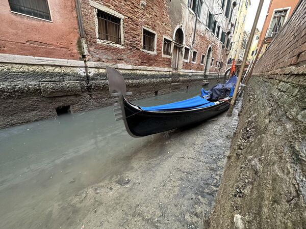 Гондола, пришвартованная вдоль канала с низким уровнем воды во время отлива в Венеции, Италия. - Sputnik Азербайджан