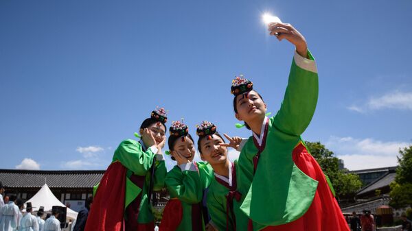 Молодые женщины в традиционных платьях ханбок после традиционной церемонии по случаю Дня совершеннолетия в деревне Намсан Ханок в Сеуле - Sputnik Азербайджан