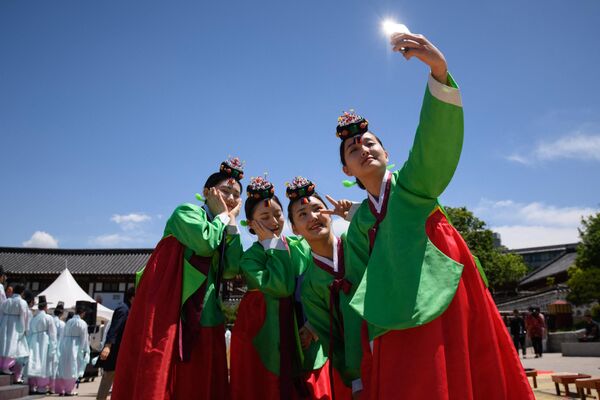 Молодые женщины в традиционных платьях ханбок после традиционной церемонии по случаю Дня совершеннолетия в деревне Намсан Ханок в Сеуле. - Sputnik Азербайджан